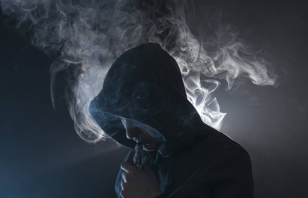 Mann zündet sich eine elektronische Zigarette mit viel Rauch an.  - Foto, Bild