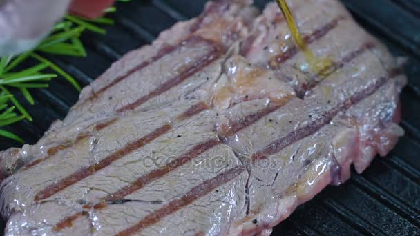 Beef steak on the grill is poured with olive oil. Slow motion. - Video, Çekim