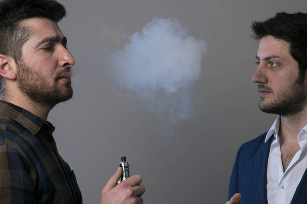 człowiek vape elektroniczny papieros z dużą ilością dymu.  - Zdjęcie, obraz