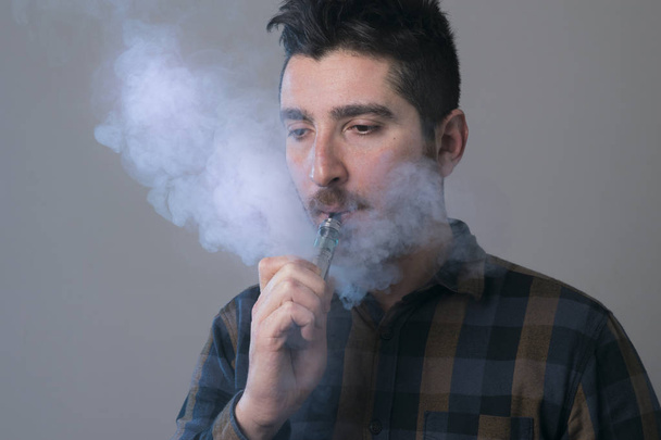 man vape an electronic cigarette with lots of smoke.  - Valokuva, kuva