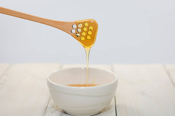 With a honey spoon a bowl is filled with flower honey - Φωτογραφία, εικόνα