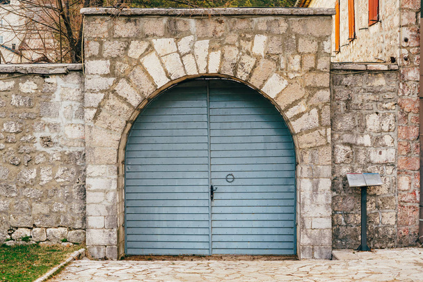 Una puerta de metal azul-gris en una valla de piedra
 - Foto, Imagen