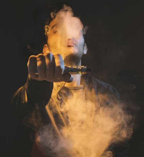 isolated man vaping e cigarette over a dark background - Foto, immagini