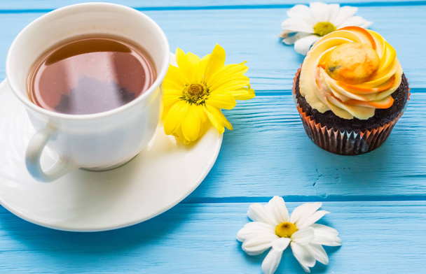 Csésze tea és sütemény a fából készült kék háttér-val csendélet - Fotó, kép