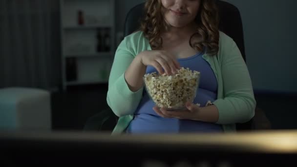 Young chubby woman laughing, commenting on TV show and eating popcorn messily - Filmmaterial, Video