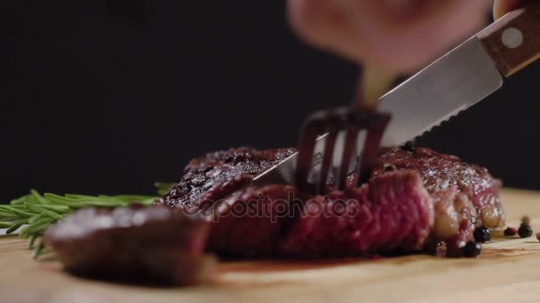 Zpomalený pohyb. Šťavnatá, svěží, chutný hovězí steak řez s nožem, držící vidličku. Detail. Grilované plátky hovězí steak na prkénku. - Záběry, video