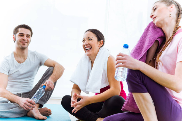 Group of people relaxing on yoga mat and talking after workout session.  - Фото, изображение