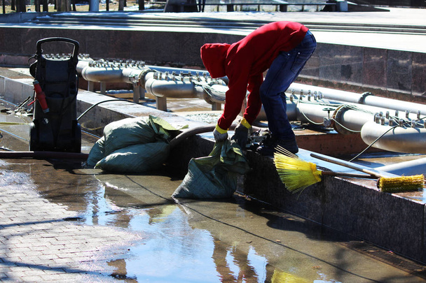 労働者は春、サンクトペテルブルクのポータブルインストールから圧力の下で洗浄する前に流域プールから土石流を削除します。 - 写真・画像