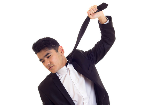 Молодой человек в костюме чинит галстук
 - Фото, изображение