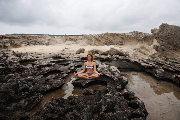 Жінка робить йогу на камені поблизу моря
 - Фото, зображення