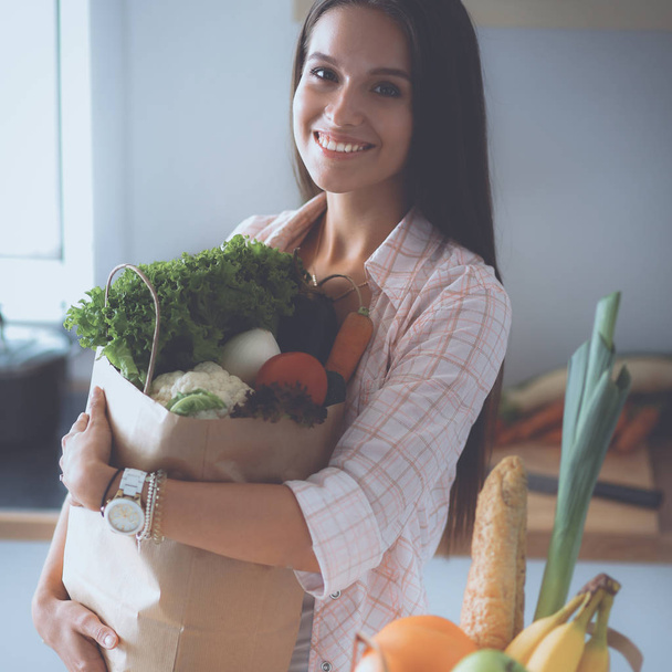 Young woman holding grocery shopping bag with vegetables - 写真・画像