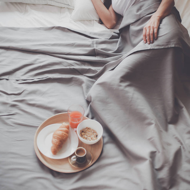 Молода жінка сидить у ліжку з чашкою молока
 - Фото, зображення