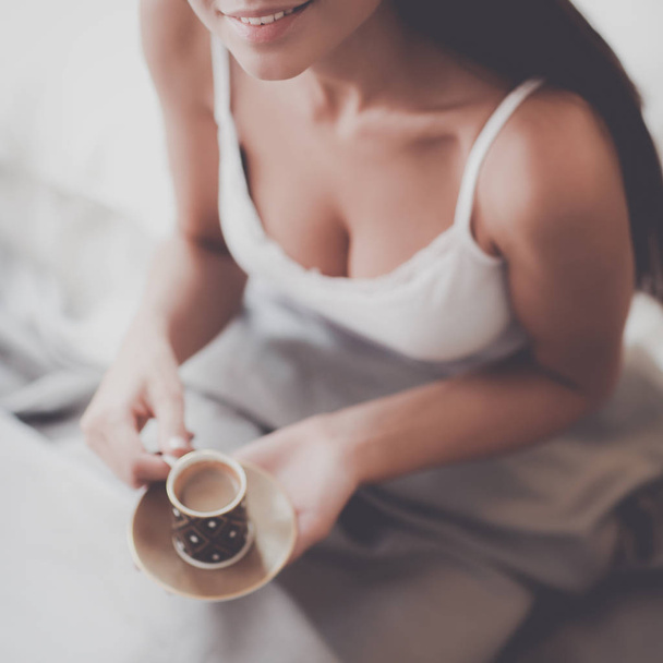 Молода жінка сидить у ліжку з чашкою молока
 - Фото, зображення
