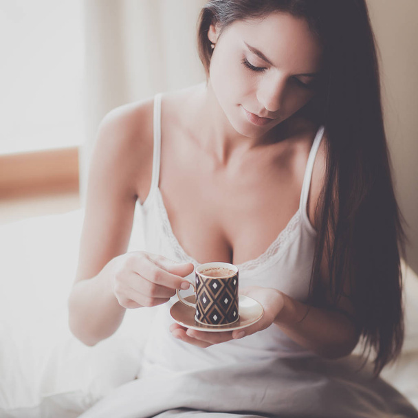 Young woman sitting in bed with a cup of milk - Valokuva, kuva