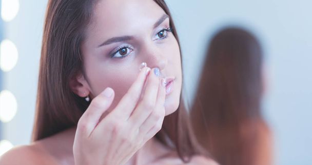 Attractive young woman applying cream on her Face - Φωτογραφία, εικόνα