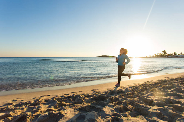 junge, gesunde Fitness-Frau läuft am Sonnenaufgangsstrand - Foto, Bild