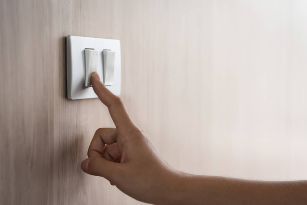 Close up hand turning on or off on grey light switch with wooden - Foto, imagen
