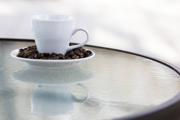 Καφέ εσπρέσο. Κόκκους καφέ σε ένα πιατάκι και ένα μικρό φλιτζάνι λευκό - Φωτογραφία, εικόνα
