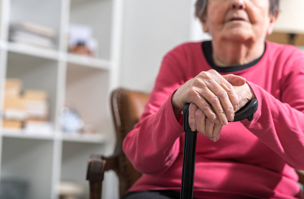 Old woman with her hands on a cane - Foto, imagen