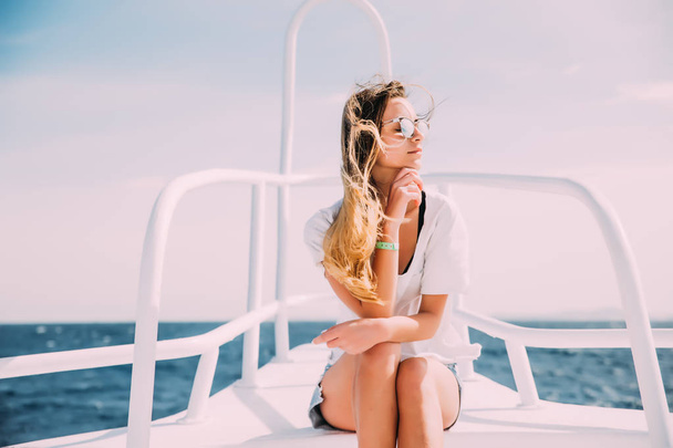 女性は海に白いヨットの鼻をリラックスします。夏休み - 写真・画像