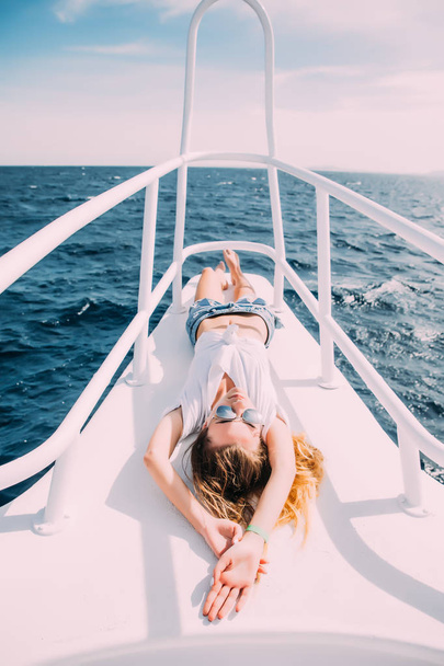 ヨットのデッキの上に横たわる少女。水着で笑顔の女性。リラックスして、あなたの休暇を楽しむ. - 写真・画像