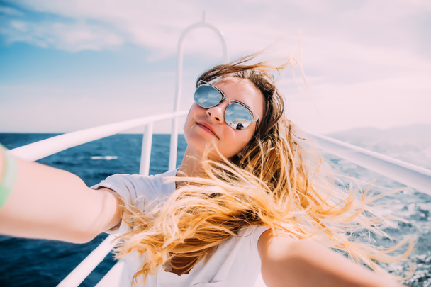Jonge vrouw nemen selfie t op het jacht drijvend in de zee - Foto, afbeelding