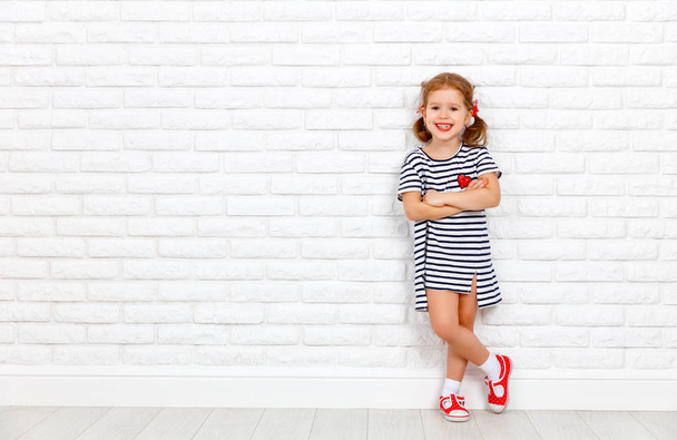 Щаслива дівчина сміється дитина біля цегляної порожньої стіни
 - Фото, зображення