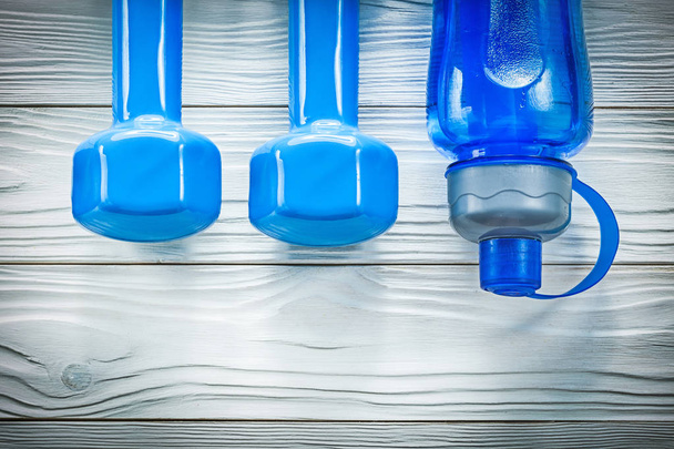 Dumbbells water bottle on wooden board sports training concept - Foto, afbeelding