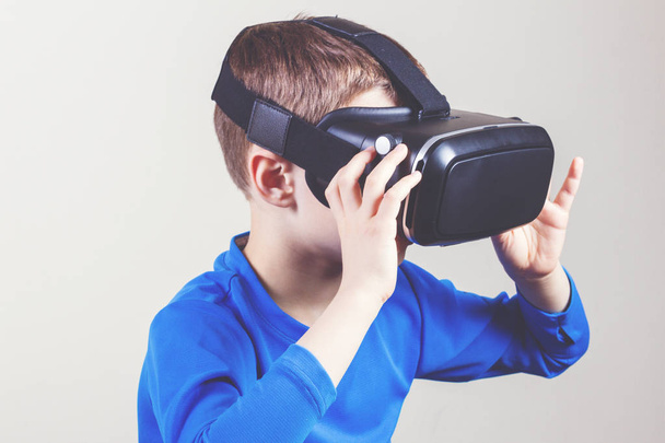 Little kid wearing virtual reality goggles watching movies or playing video games - Fotografie, Obrázek