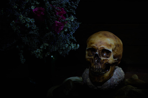 Κρανίο με κολοκύθι και λουλούδι στο βάζο σε σκοτεινή νύχτα - Φωτογραφία, εικόνα