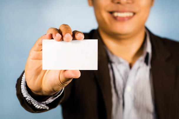 Uomo d'affari asiatico mostra carta bianca a portata di mano e sorridere. carta vuota
 - Foto, immagini