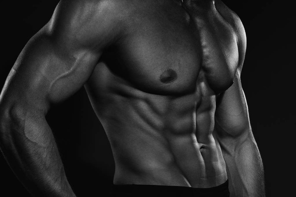 Güçlü sağlıklı yakışıklı atletik erkek Fitness modeli koyu gri duvara yakın poz portresi - Fotoğraf, Görsel