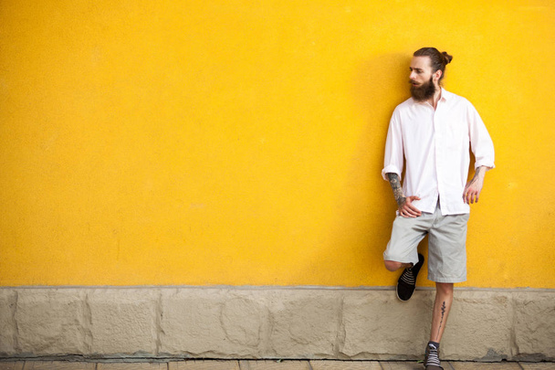 Cool tattooed bearded hipster on yellow wall - Valokuva, kuva