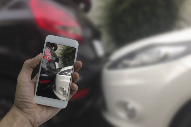Ręka trzyma inteligentny telefon wziąć zdjęcie na scenie cras samochodu - Zdjęcie, obraz
