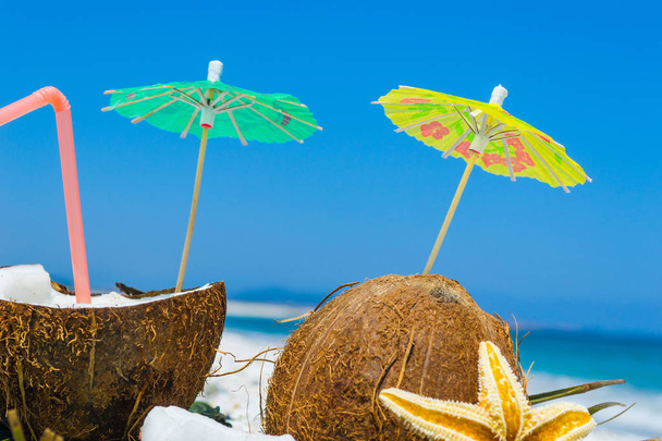 Cocktail umbrellas in coconuts halves  - Fotografie, Obrázek