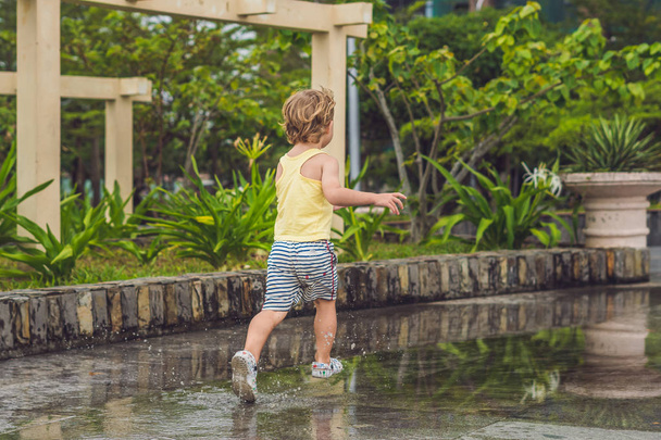 Little boy runs through a puddle - Foto, afbeelding