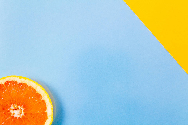 Enkele grapefruit slice close-up op blauw en diagonale geel terug - Foto, afbeelding