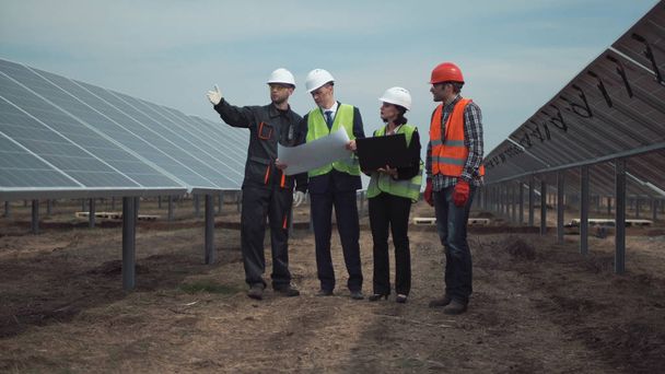 Grupo de engenheiros ou técnicos em uma fazenda solar
 - Foto, Imagem