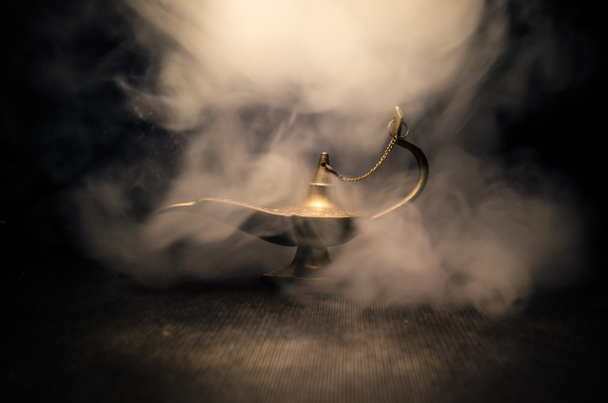 Antieke Aladdin Arabische nachten genie stijl olielamp met zachte lichte witte rook, donkere achtergrond. Lamp van wensen concept. Toned - Foto, afbeelding