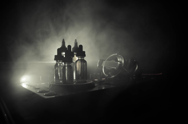 Concepto de Vape y DJ Club. Nubes de humo y botellas de vapor líquido en Dj mezclador de cerca. Efectos de luz. Útil como fondo o publicidad de vapor o club o fondo de vapor
. - Foto, imagen