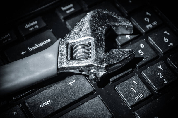 Wrench tool over a laptop on a dark background close up selective focus - Photo, Image