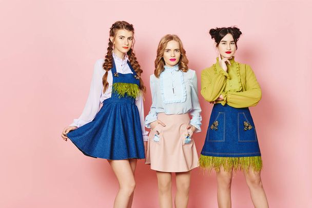 Photo de mode de trois jeunes filles posant sur fond rose en studio
 - Photo, image