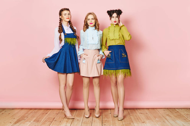 Модное фото трех молодых девушек, позирующих на розовом фоне в студии
 - Фото, изображение
