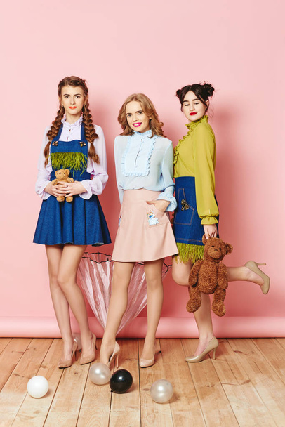 Fotografia mody, trzy młode dziewczyny pozowanie różowy tło w studio - Zdjęcie, obraz