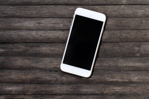 White smartphone on dark wooden table. Black screen smartphone on shabby chic background. - Φωτογραφία, εικόνα