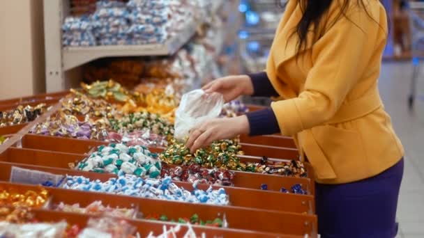 Eine Frau kauft in einem Geschäft Süßigkeiten. sie steckt sie in das Paket - Filmmaterial, Video