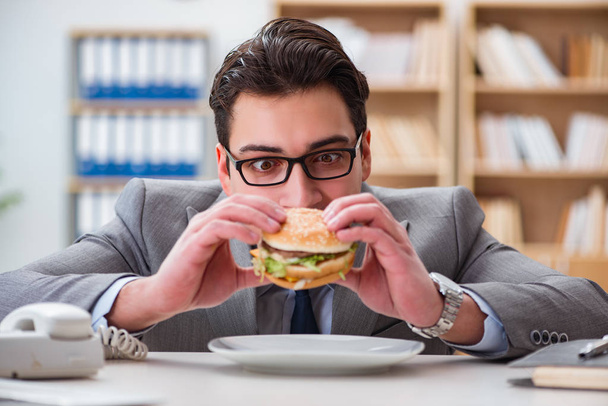 空腹面白いビジネスマンがジャンクフードサンドイッチを食べる - 写真・画像