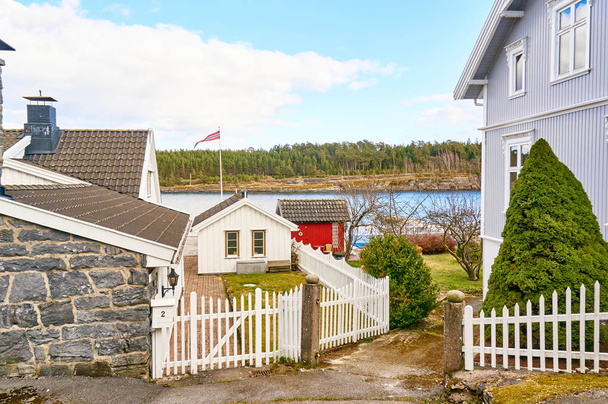 Nostalgic Norwegian alley, a wooden fence in front of white hous - Фото, изображение