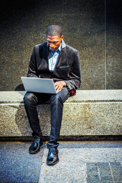 Молодой афроамериканец работает на ноутбуке снаружи в
 - Фото, изображение