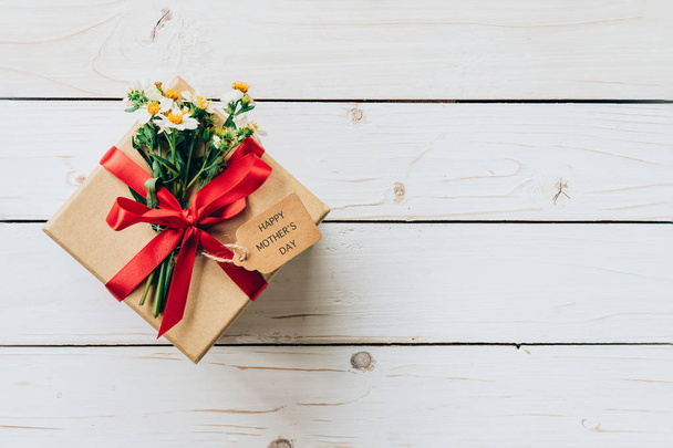 Ruskea lahjapakkaus ja kukka puupöydällä läsnä, äitienpäivä co
 - Valokuva, kuva